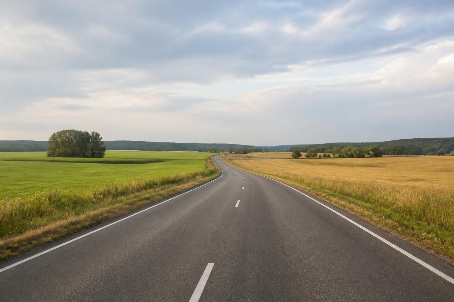 Quiet rural road with open fields on both sides.